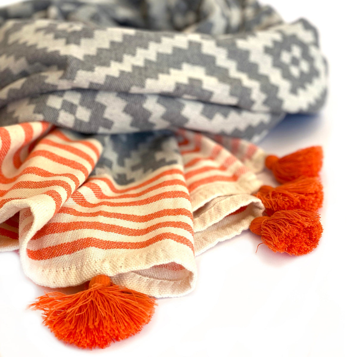 Closeup of the Hilana Merida towel's orange striped border and orange tassels