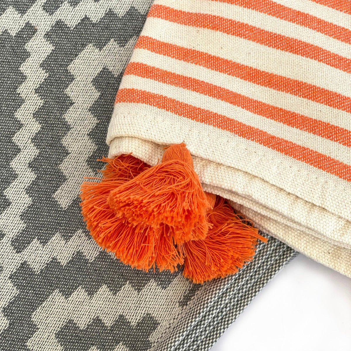 Orange tassels on the cream band of the gray diamond-weave Hilana Merida Turkish towel