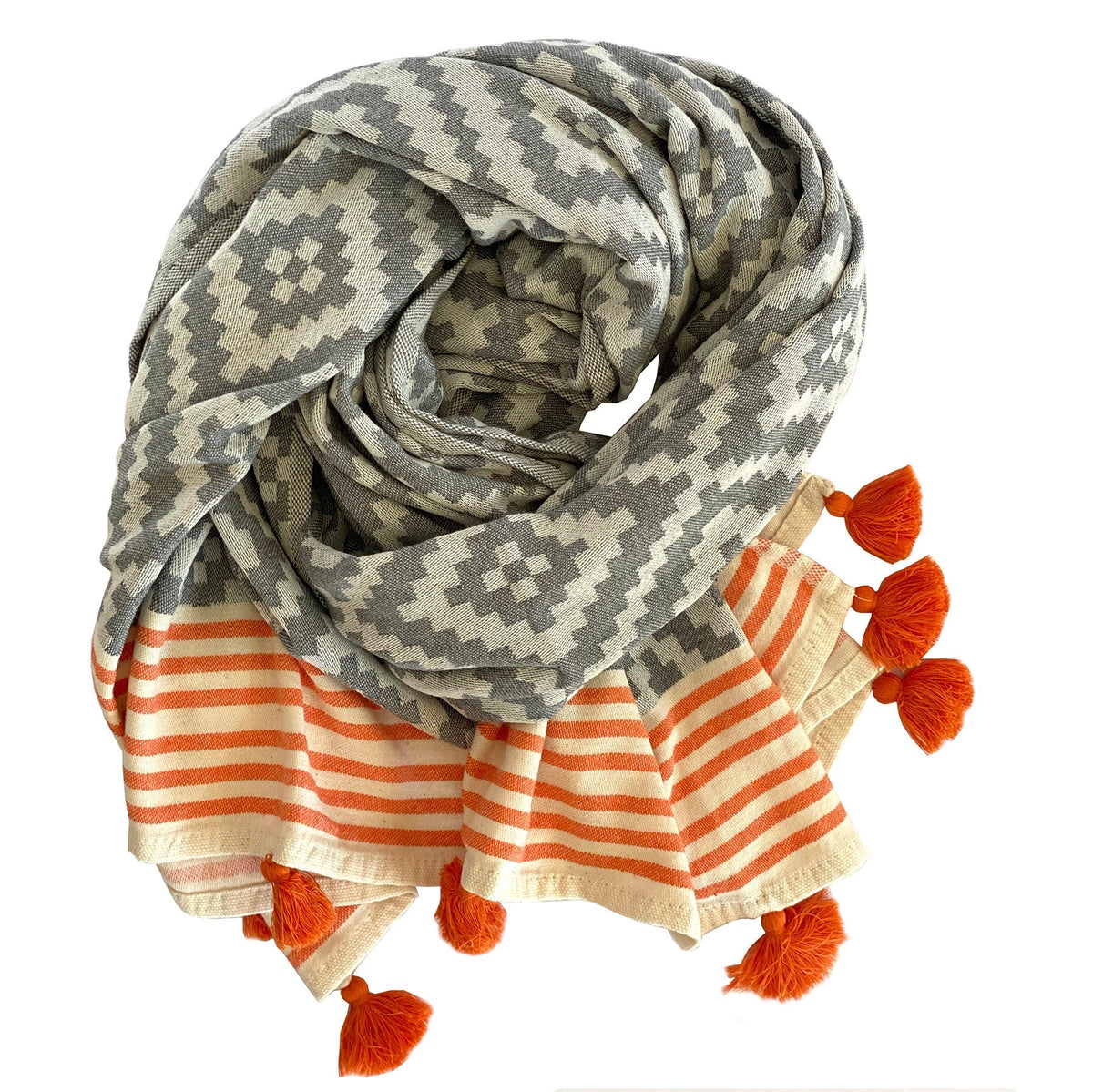 Gray and cream Hilana Merida Turkish beach towel rolled up showing its orange-striped ends and tassels