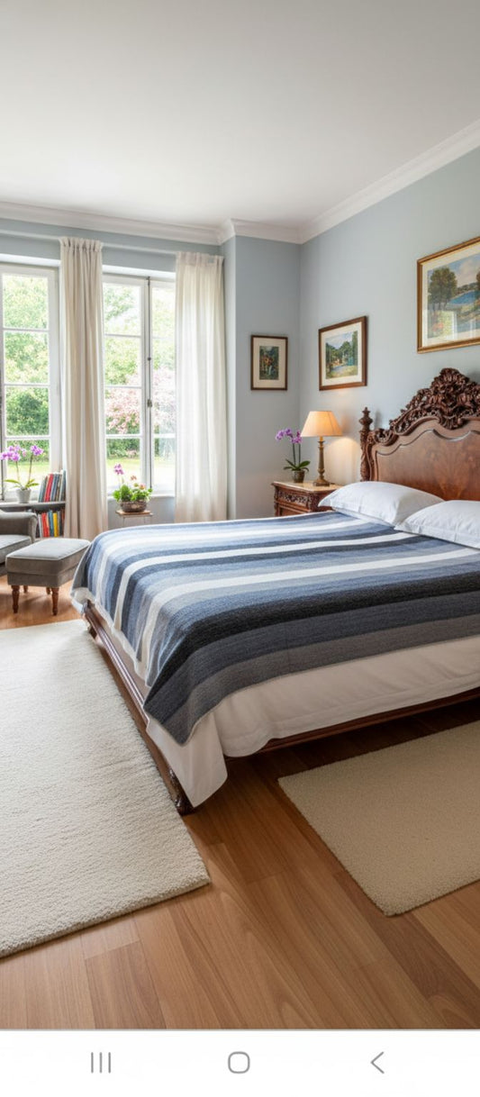Gray and white striped alpaca bed blanket styled on a dark wood bed