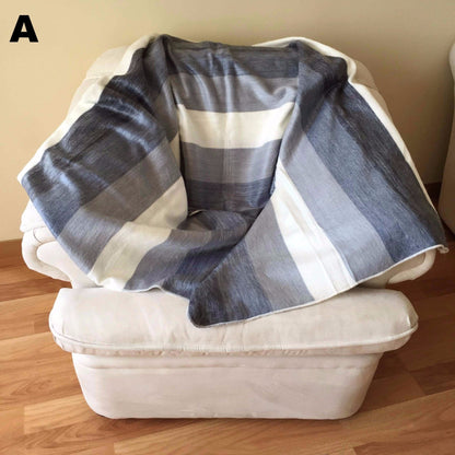 Gray and white striped alpaca bed blanket draped over a white armchair