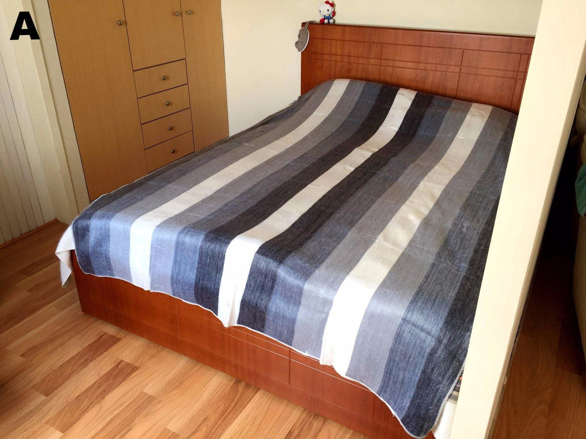 Gray and white striped alpaca bed blanket spread over a wooden bed