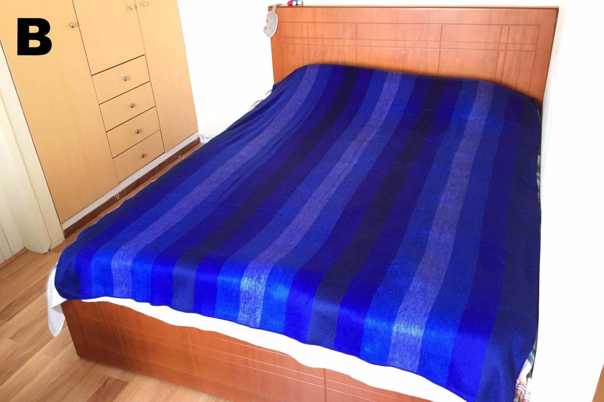 Blue and white striped alpaca bed blanket styled on a bed