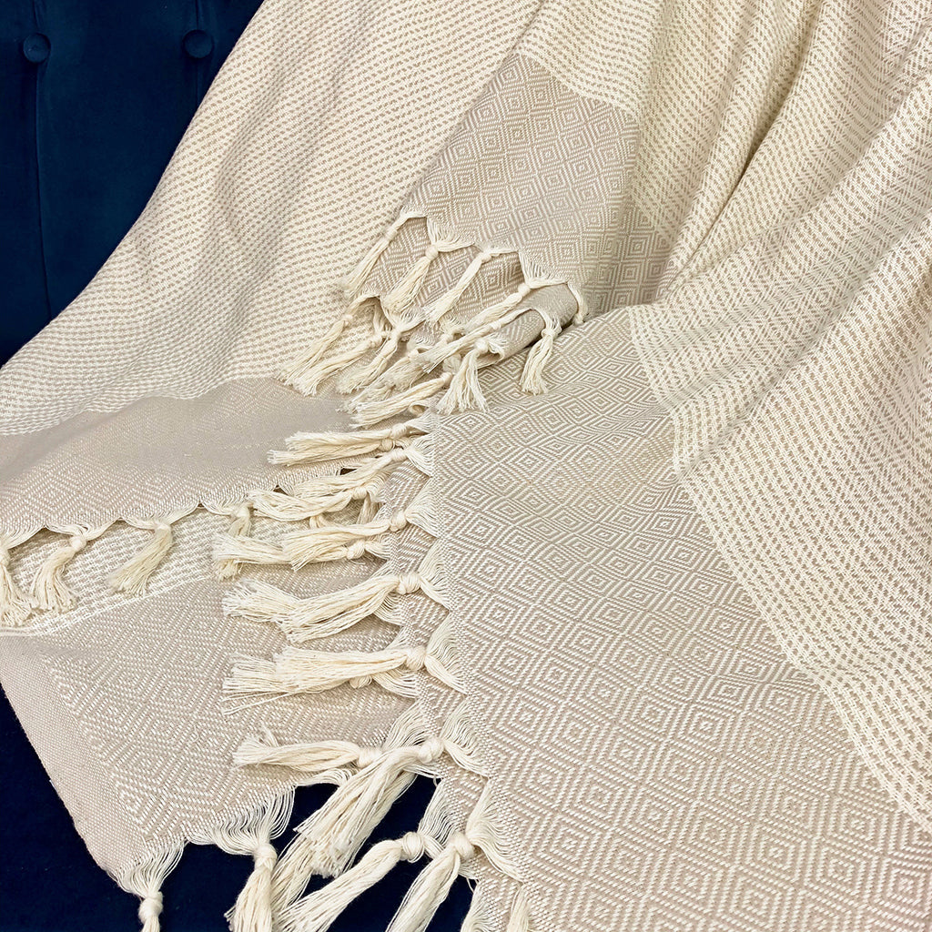 Beige diamond stripe Turkish throws with tassel fringe draped over a navy chair
