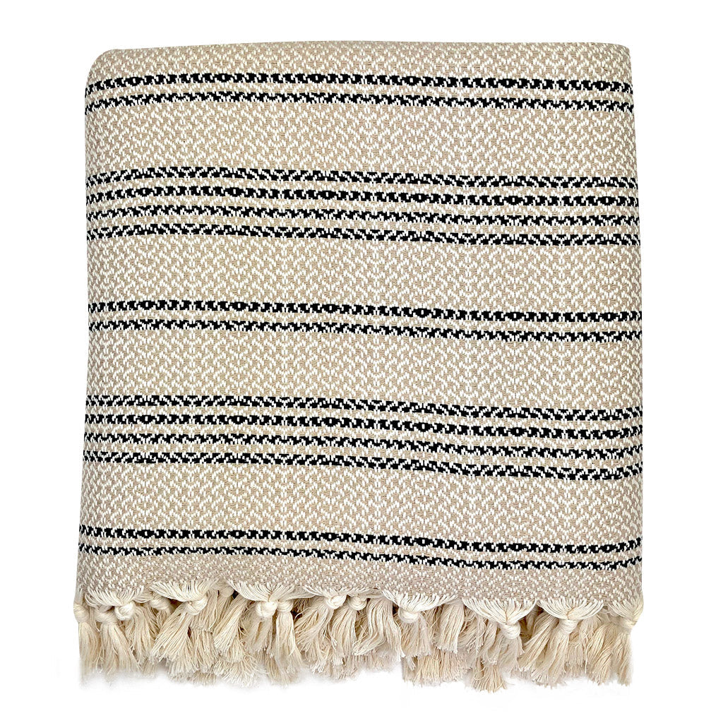 Folded beige and cream woven stripe Turkish throw with cream tassels