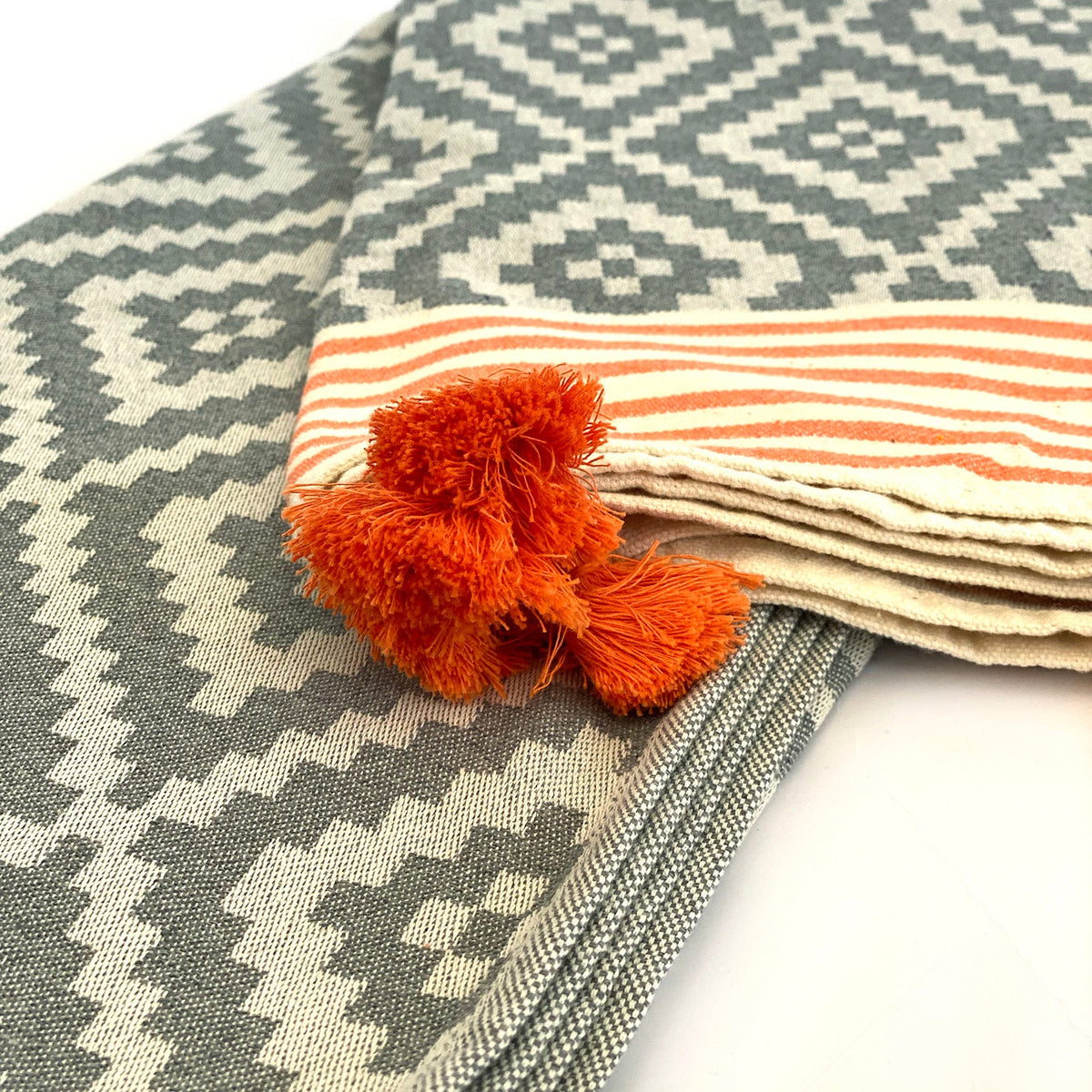 Folded cream edge with orange stripes and tassels on the gray Hilana Merida Turkish towel