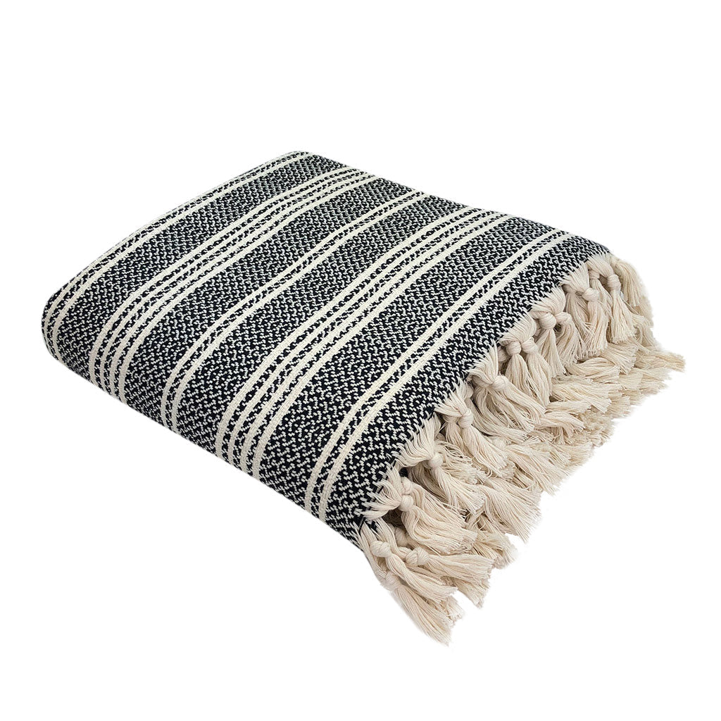 Folded black and white striped Turkish blanket with knotted fringe, angled view
