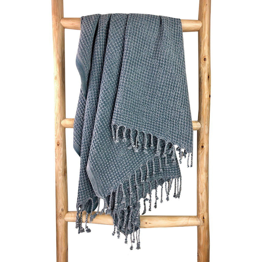 Blue gray waffle weave Turkish towel hanging over a wooden ladder