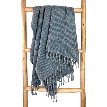 Blue gray waffle weave Turkish towel hanging over a wooden ladder