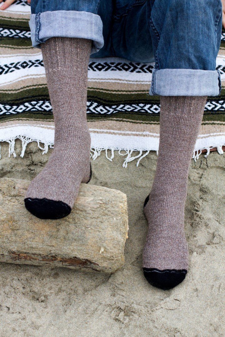 Brown OutdoorAdventure alpaca socks with black toes worn with cuffed jeans on sand