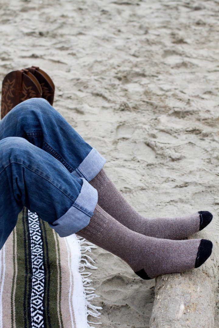 Person relaxing on a beach blanket in brown OutdoorAdventure alpaca socks with black toes