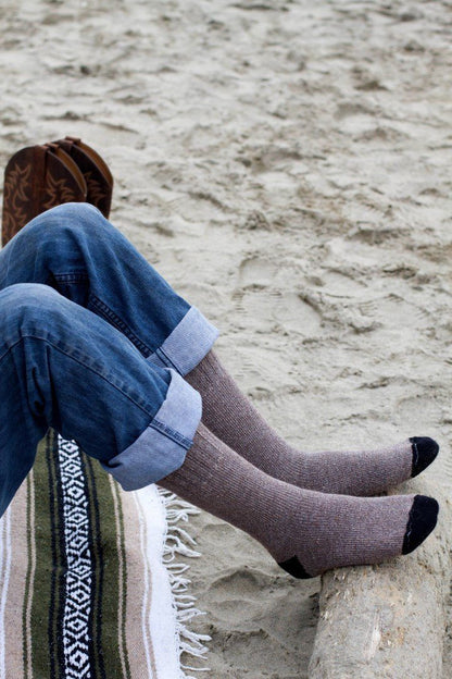 Person relaxing on a beach blanket in brown OutdoorAdventure alpaca socks with black toes