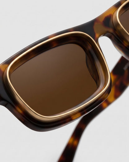 Closeup of the Rae matte tortoise rectangular sunglasses' gold-rimmed brown lens