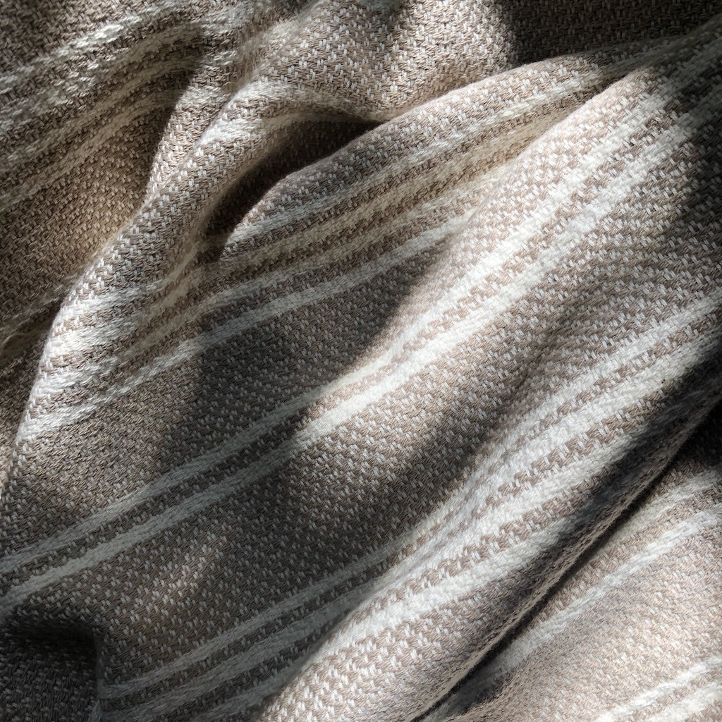 Sunlit closeup of a gray and white striped woven Turkish throw