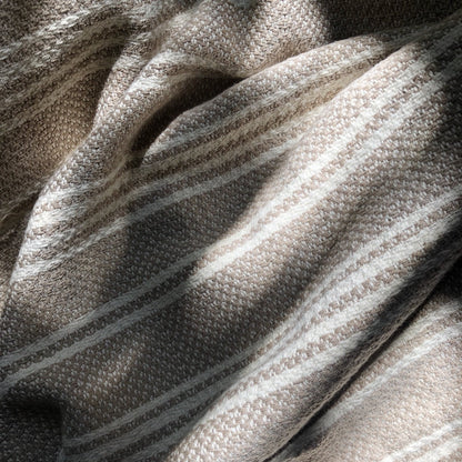Sunlit closeup of a gray and white striped woven Turkish throw