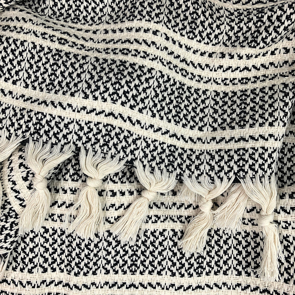 Closeup of knotted cream tassels on a black and cream striped woven throw