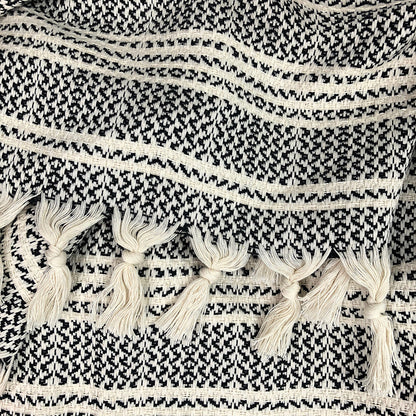 Closeup of knotted cream tassels on a black and cream striped woven throw