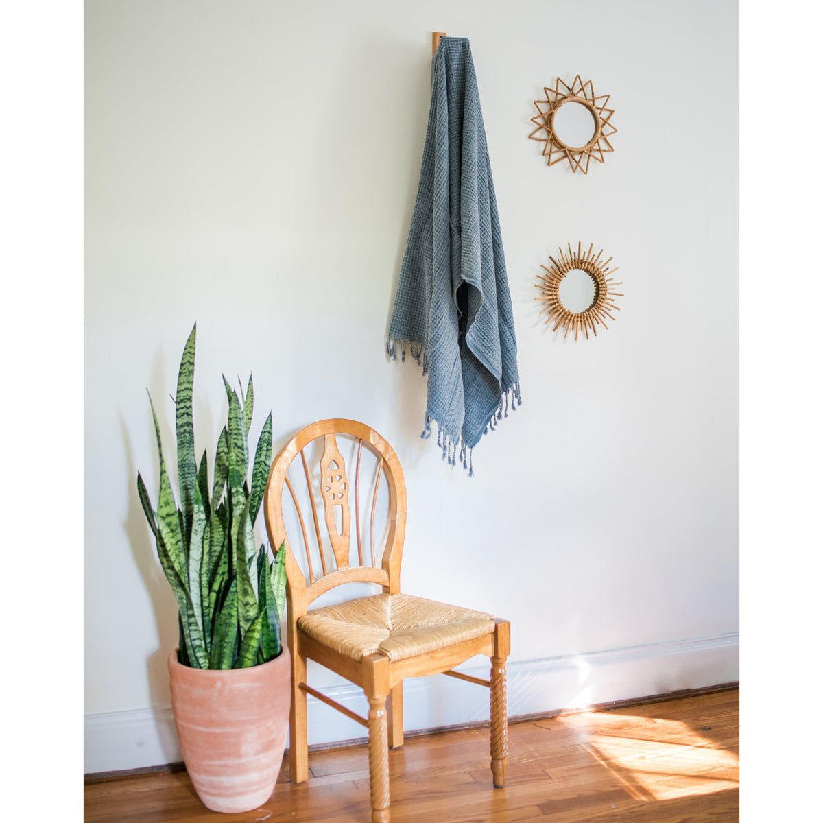 Blue waffle weave Turkish towel hanging on a wall hook above a wooden chair