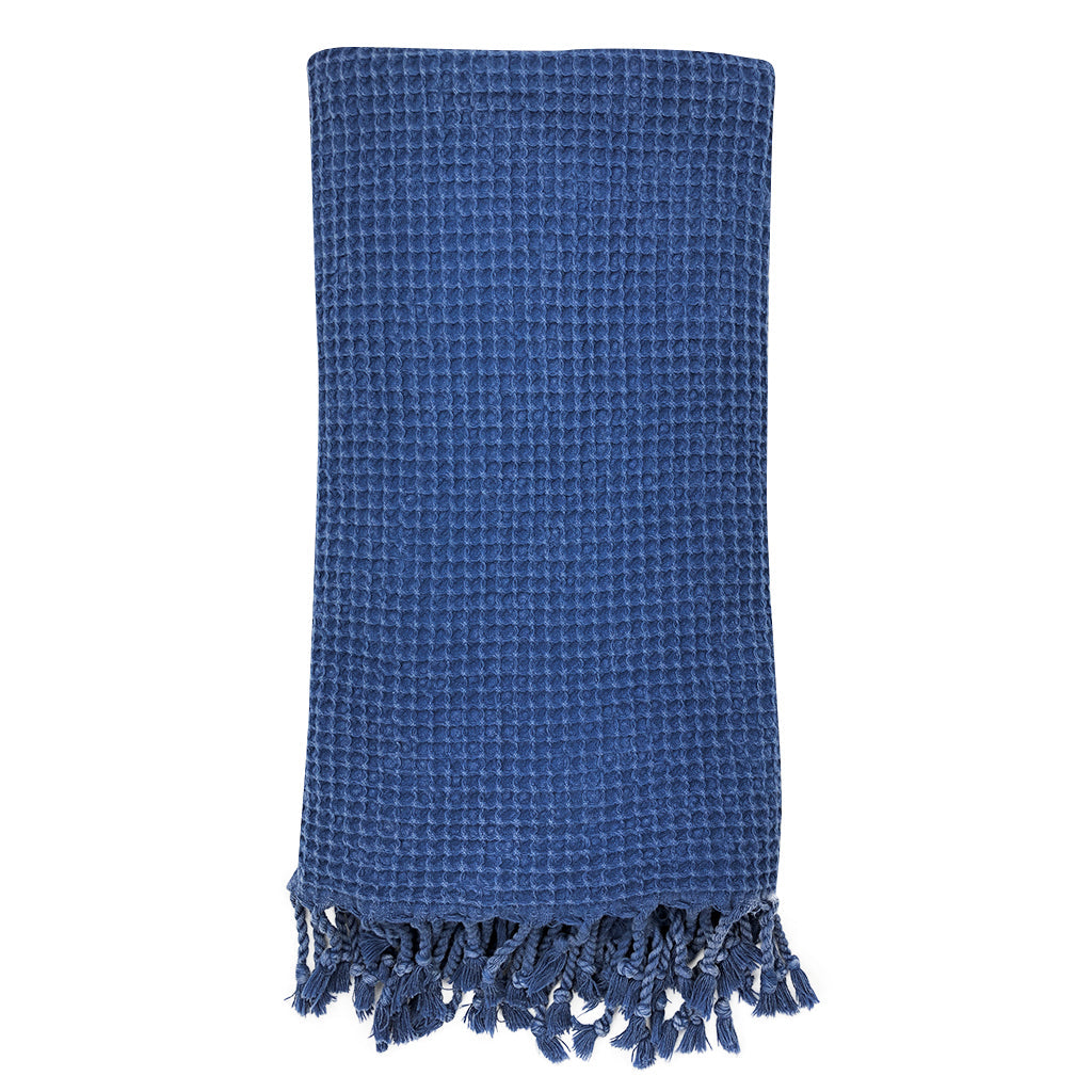 Folded deep blue waffle weave Turkish towel with twisted fringe